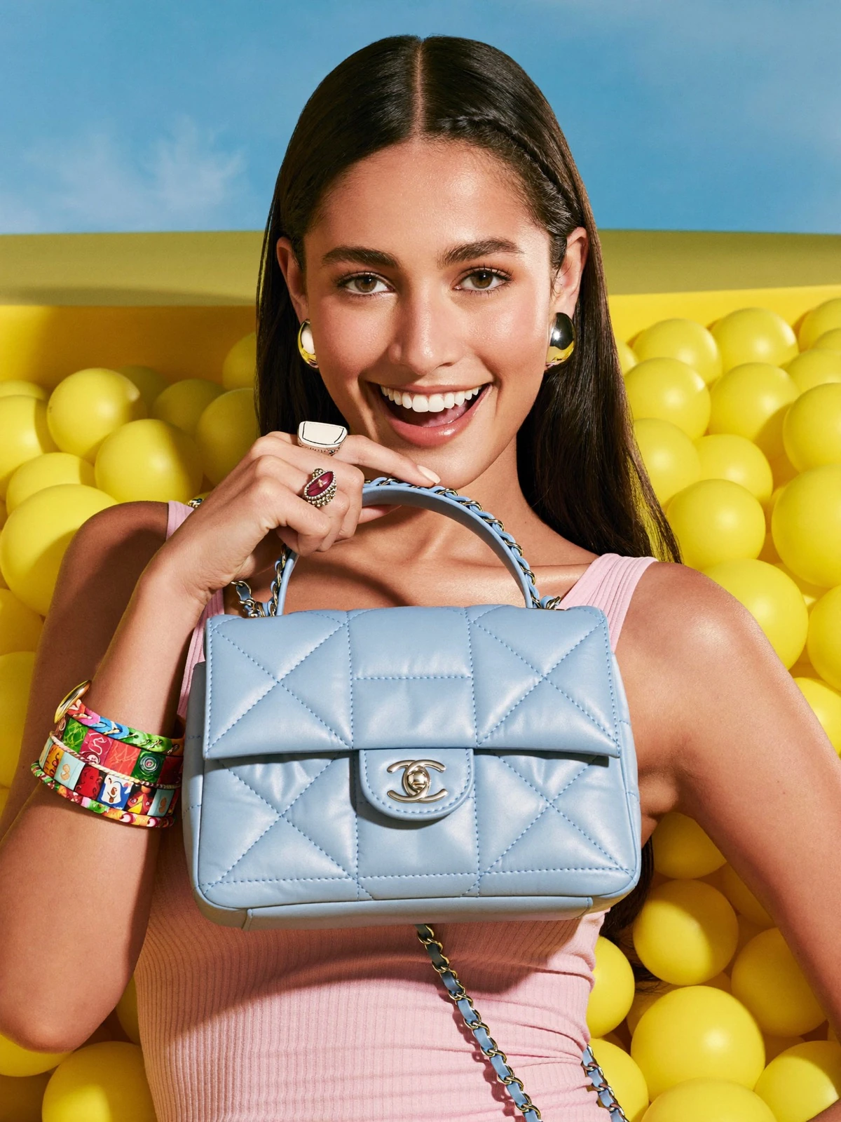 AI campaign photo of a woman holding a quilted blue handbag in a yellow ball pit, by KAMIS STUDIO